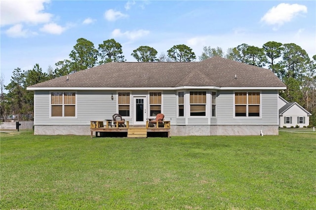 back of property with a deck, a yard, and roof with shingles