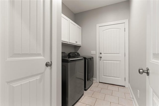 washroom featuring baseboards, cabinet space, washing machine and dryer, and light tile patterned flooring