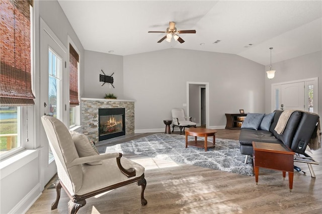 living area featuring plenty of natural light, a stone fireplace, and wood finished floors