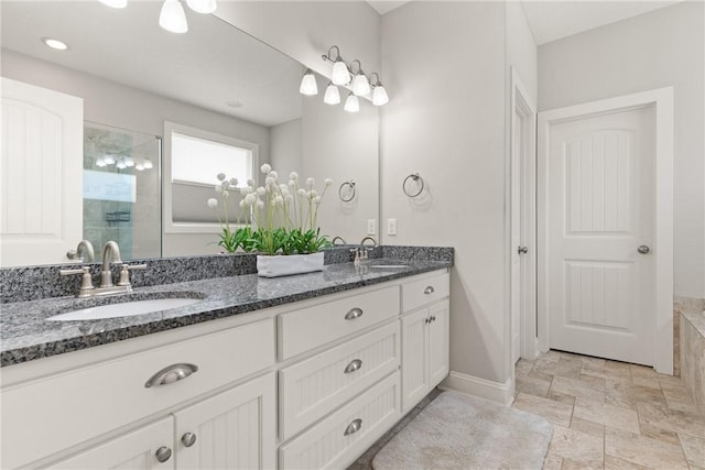 bathroom with a sink, stone finish flooring, a stall shower, and double vanity