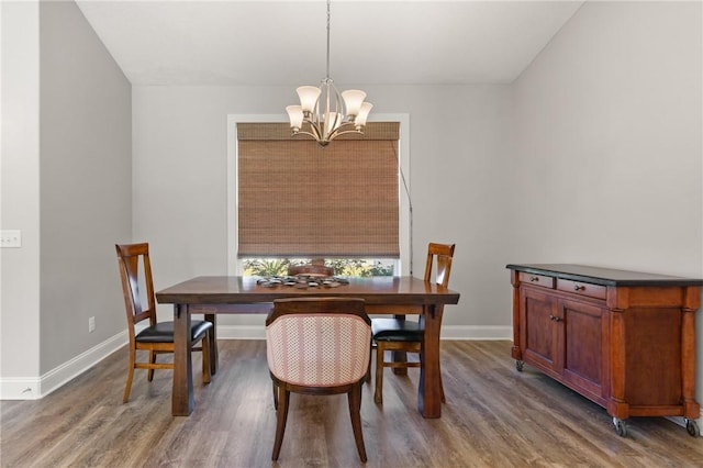 dining room with a notable chandelier, baseboards, and wood finished floors