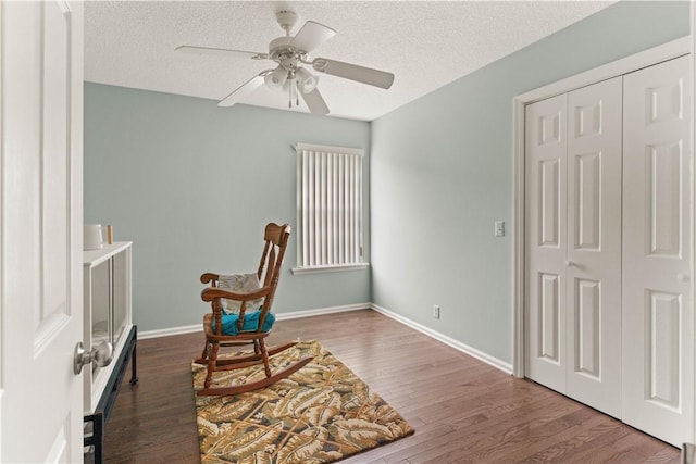 living area with a textured ceiling, dark hardwood / wood-style floors, and ceiling fan