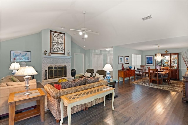 living room with a tile fireplace, ceiling fan, dark wood-type flooring, and vaulted ceiling