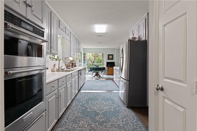 kitchen with gray cabinetry, sink, dark hardwood / wood-style floors, a textured ceiling, and stainless steel appliances