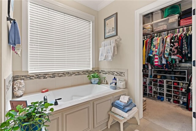 bathroom with ornamental molding and a tub to relax in