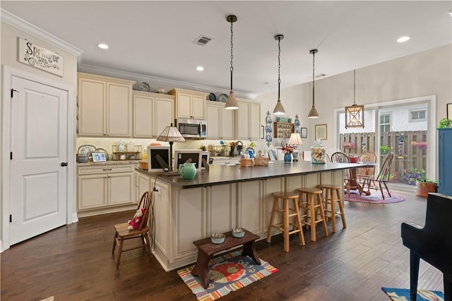 kitchen featuring a kitchen island, hanging light fixtures, cream cabinetry, and dark wood-type flooring