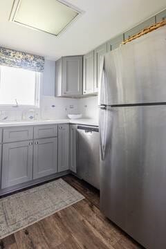 kitchen featuring light countertops, dark wood-style floors, gray cabinets, and appliances with stainless steel finishes