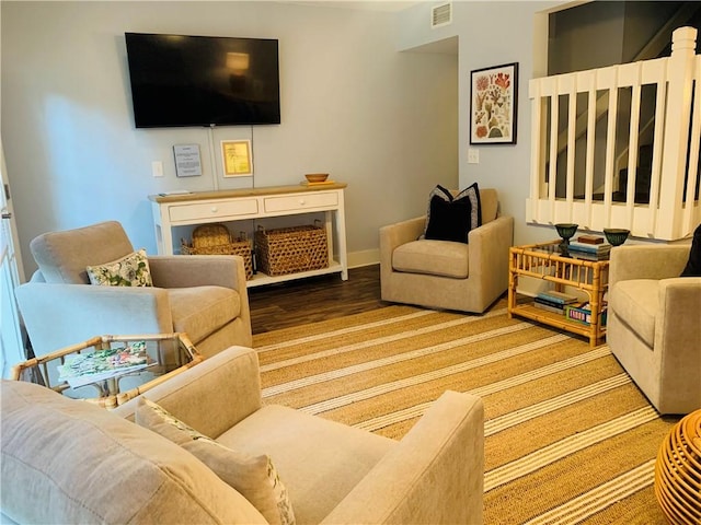 living room with wood finished floors, visible vents, and baseboards