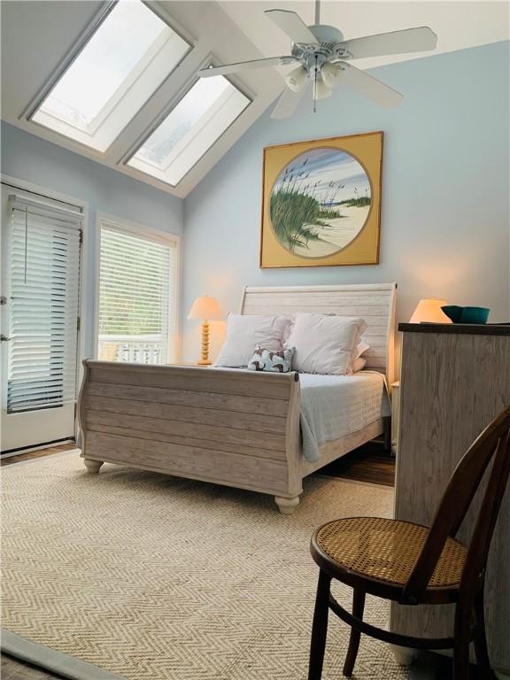 carpeted bedroom featuring lofted ceiling with skylight, ceiling fan, and access to outside