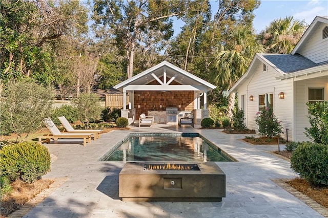 view of swimming pool featuring an outbuilding, a fire pit, area for grilling, and a patio