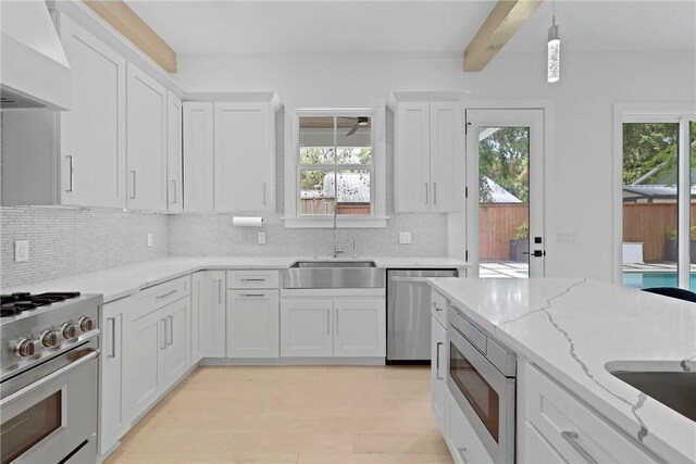 4 Lake View Cottages Ct, Saint Simons Island, GA 31522 - kitchen featuring appliances with stainless steel finishes, custom range hood, a sink, white cabinets, and backsplash