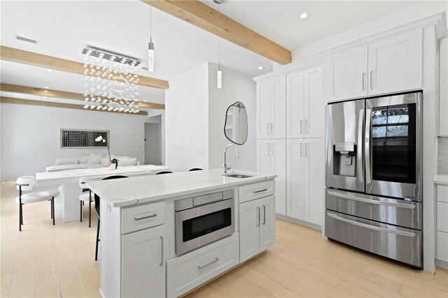 4 Lake View Cottages Ct, Saint Simons Island, GA 31522 - kitchen featuring appliances with stainless steel finishes, a sink, beam ceiling, open floor plan, and light wood-style flooring