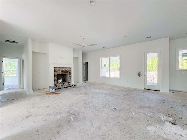 unfurnished living room with a wealth of natural light, a fireplace, visible vents, and a ceiling fan