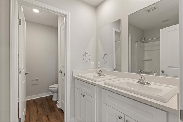 bathroom with wood-type flooring, vanity, toilet, and walk in shower