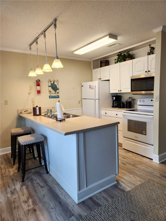 1175 N Beachview Dr Unit 286, Jekyll Island, GA 31527 - kitchen with pendant lighting, sink, white appliances, white cabinetry, and kitchen peninsula