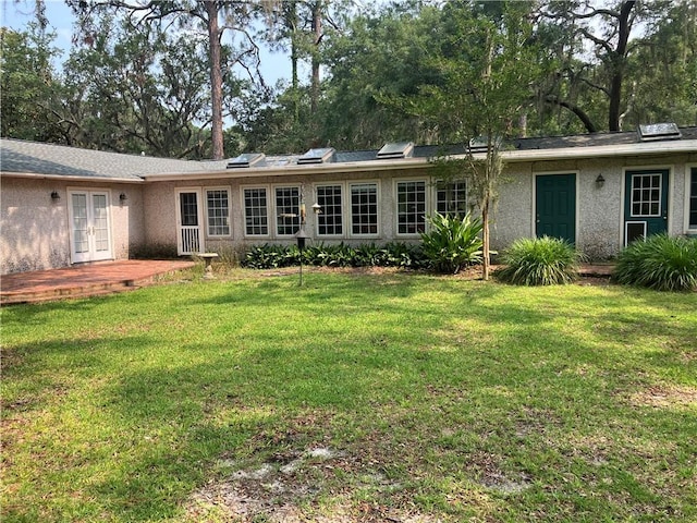 7 Hyde Ave, Jekyll Island, GA 31527 - back of house featuring french doors, a lawn, and stucco siding