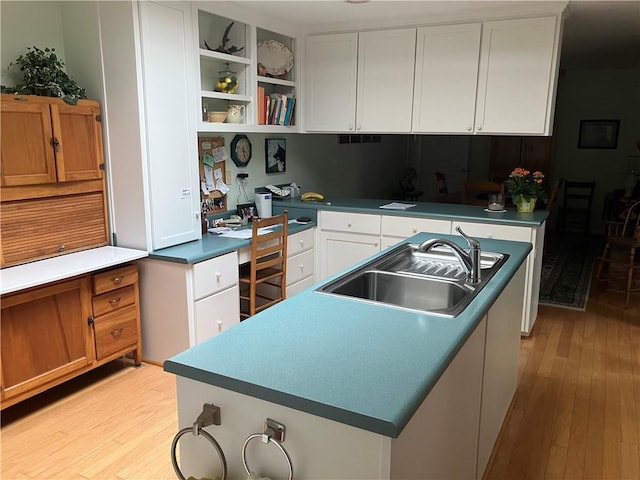 7 Hyde Ave, Jekyll Island, GA 31527 - kitchen featuring a sink, light wood-style flooring, white cabinets, open shelves, and a kitchen island with sink