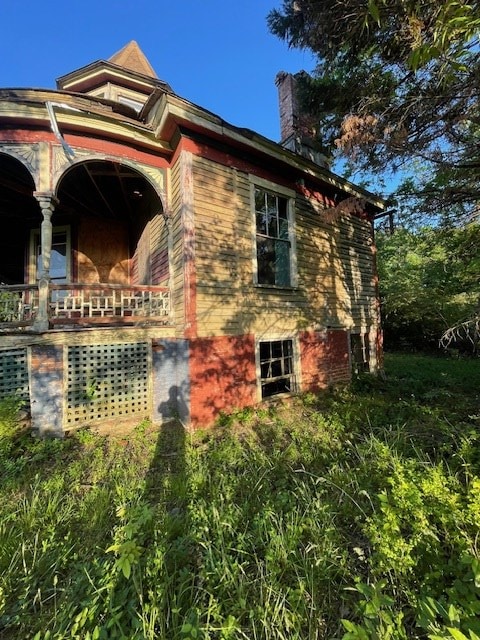 view of side of property featuring a porch and a chimney