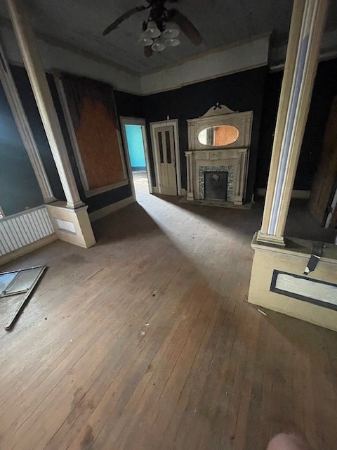 unfurnished living room with a fireplace, ceiling fan, hardwood / wood-style flooring, and decorative columns