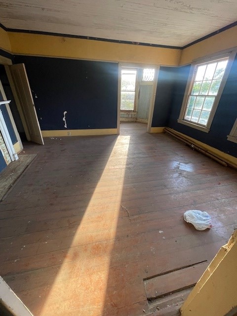 spare room with baseboards, crown molding, and wood-type flooring
