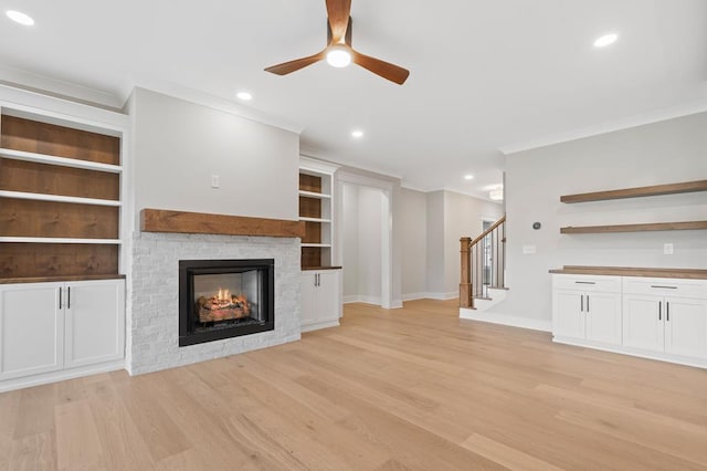 unfurnished living room featuring ceiling fan, light hardwood / wood-style floors, built in features, and a fireplace