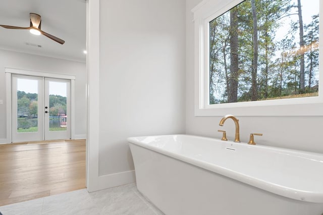 bathroom with a bathing tub, a wealth of natural light, french doors, and ceiling fan