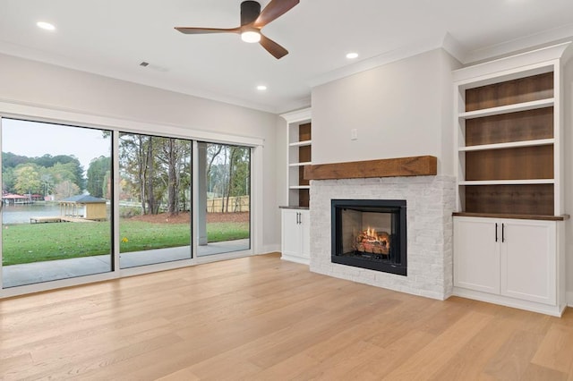 unfurnished living room with built in shelves, light hardwood / wood-style flooring, ceiling fan, and a tiled fireplace