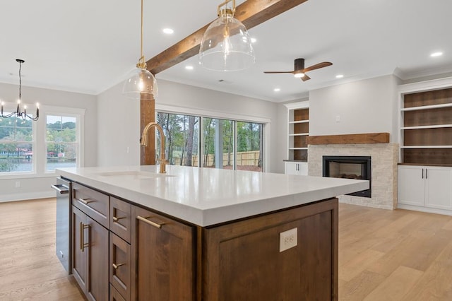 kitchen featuring sink, an island with sink, decorative light fixtures, and built in features