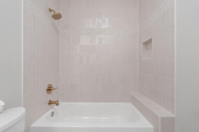 bathroom with tiled shower / bath combo and toilet