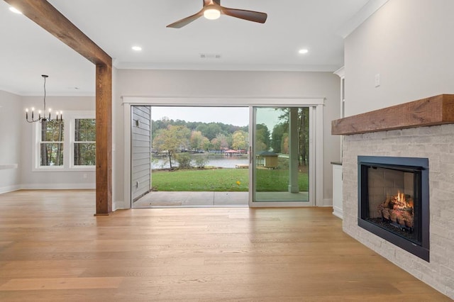 entryway with plenty of natural light, ceiling fan with notable chandelier, a tile fireplace, and light hardwood / wood-style flooring