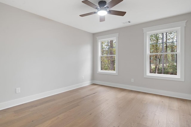 empty room with a wealth of natural light, ceiling fan, and light hardwood / wood-style floors