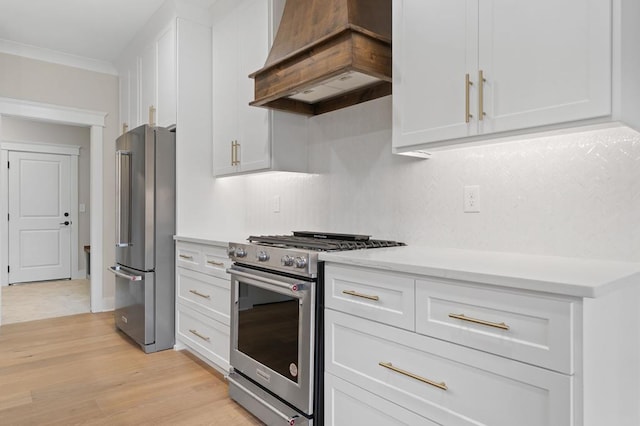 kitchen with premium range hood, light wood-type flooring, high quality appliances, white cabinets, and ornamental molding