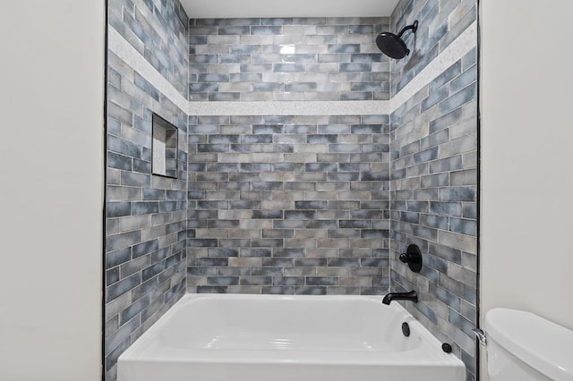 bathroom with toilet and tiled shower / bath