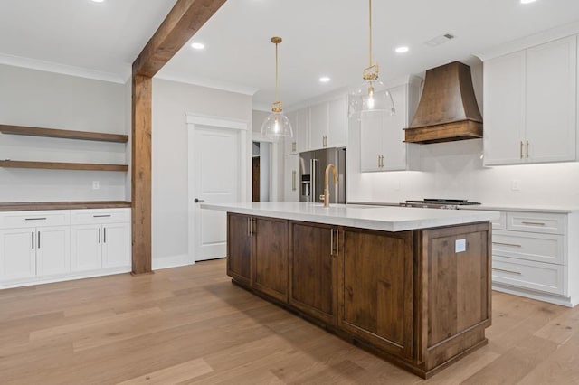 kitchen with a center island with sink, pendant lighting, custom range hood, and high quality fridge