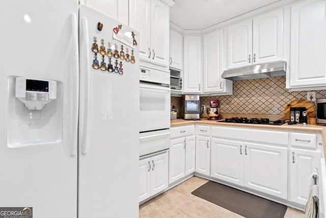 kitchen featuring white appliances, white cabinetry, a warming drawer, under cabinet range hood, and tasteful backsplash