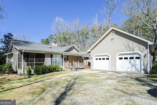 ranch-style house with a sunroom, a garage, a chimney, and driveway