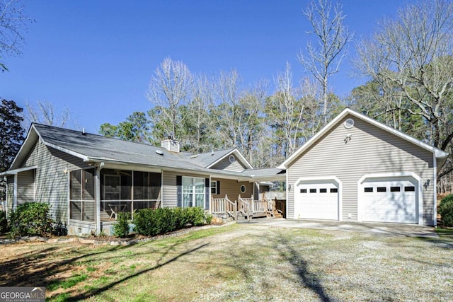 single story home featuring an attached garage, a sunroom, a chimney, a front yard, and driveway