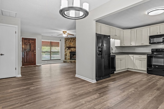 108 Ashwood Pt, Eatonton, GA 31024 - kitchen with black appliances, dark countertops, dark wood-style flooring, ceiling fan, and white cabinetry