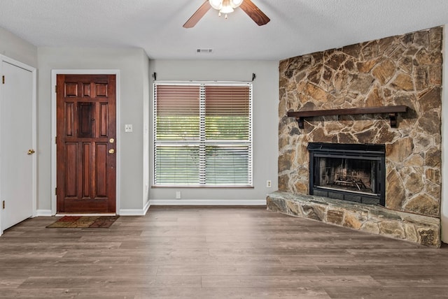 108 Ashwood Pt, Eatonton, GA 31024 - unfurnished living room featuring ceiling fan, a fireplace, wood finished floors, a textured ceiling, and baseboards