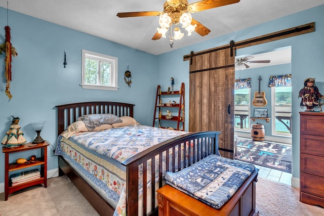 carpeted bedroom featuring a barn door, ceiling fan, and a textured ceiling