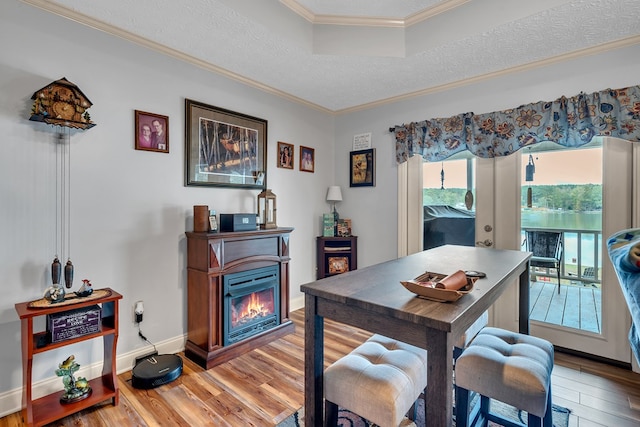 dining room with hardwood / wood-style floors, a textured ceiling, a tray ceiling, and crown molding