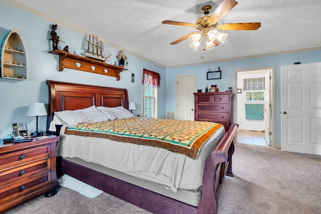 carpeted bedroom featuring ceiling fan, ornamental molding, ensuite bathroom, and multiple windows