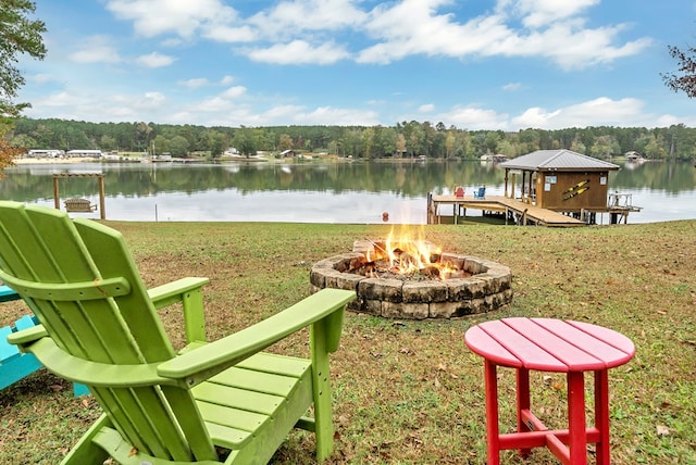 dock area with a fire pit, a water view, and a lawn