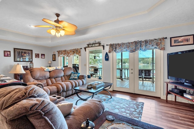 living room with hardwood / wood-style floors, ceiling fan, a textured ceiling, and a tray ceiling