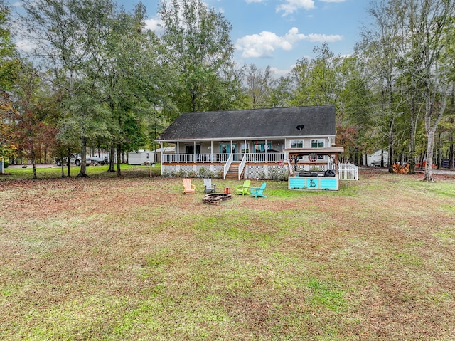 rear view of house featuring a fire pit, covered porch, and a lawn