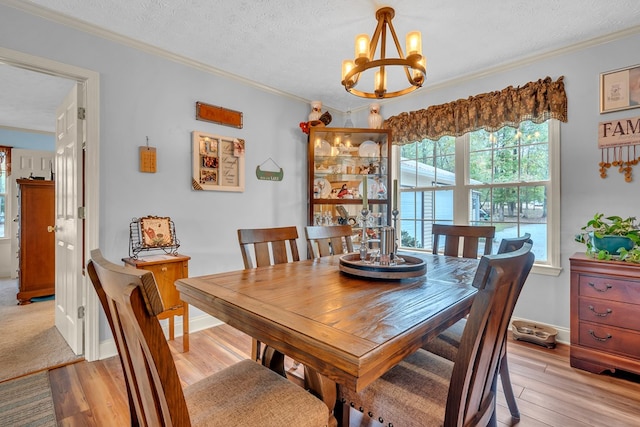 dining room with ornamental molding, light wood-type flooring, a textured ceiling, and an inviting chandelier