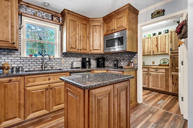 kitchen with stainless steel microwave, sink, a center island, dark stone countertops, and hardwood / wood-style floors