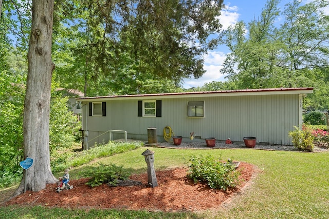 back of property featuring a lawn and metal roof