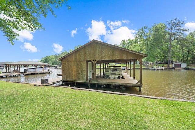 dock area with boat lift, a lawn, and a water view