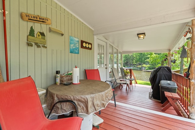 deck with covered porch and a water view